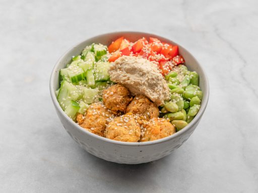 Frisch zubereitete Bowl mit Gurke, Edamame, Paprika, Falafel und Hummus