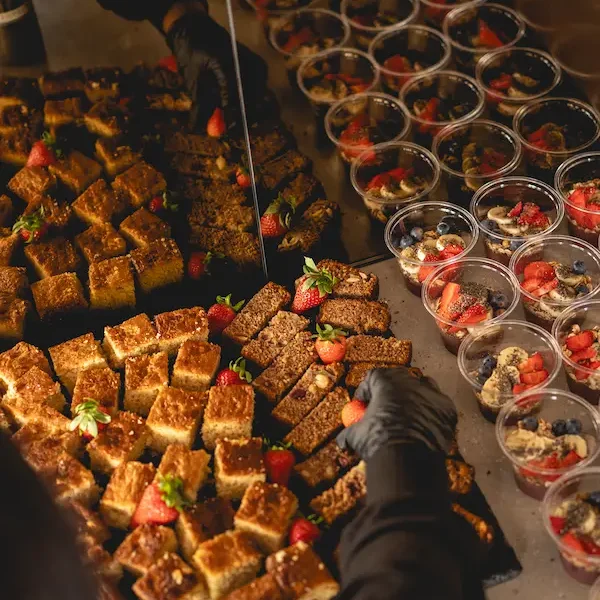 Bananabread, Kuchen und Acai-Bowls und eine Hand, die darauf Erdbeeren verteilt