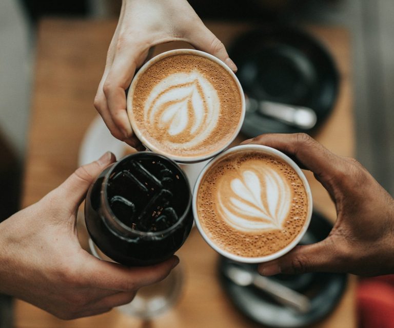 3 Tassen Kaffee, die zum Anstoßen in die Mitte gehalten werden